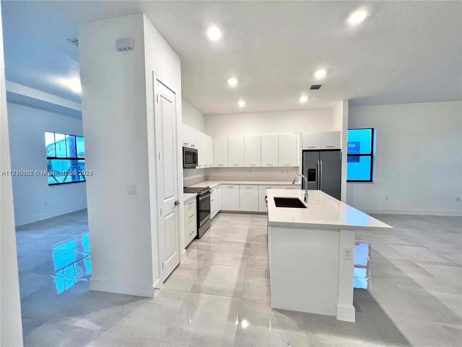 a kitchen with a sink a stove a refrigerator and white cabinets