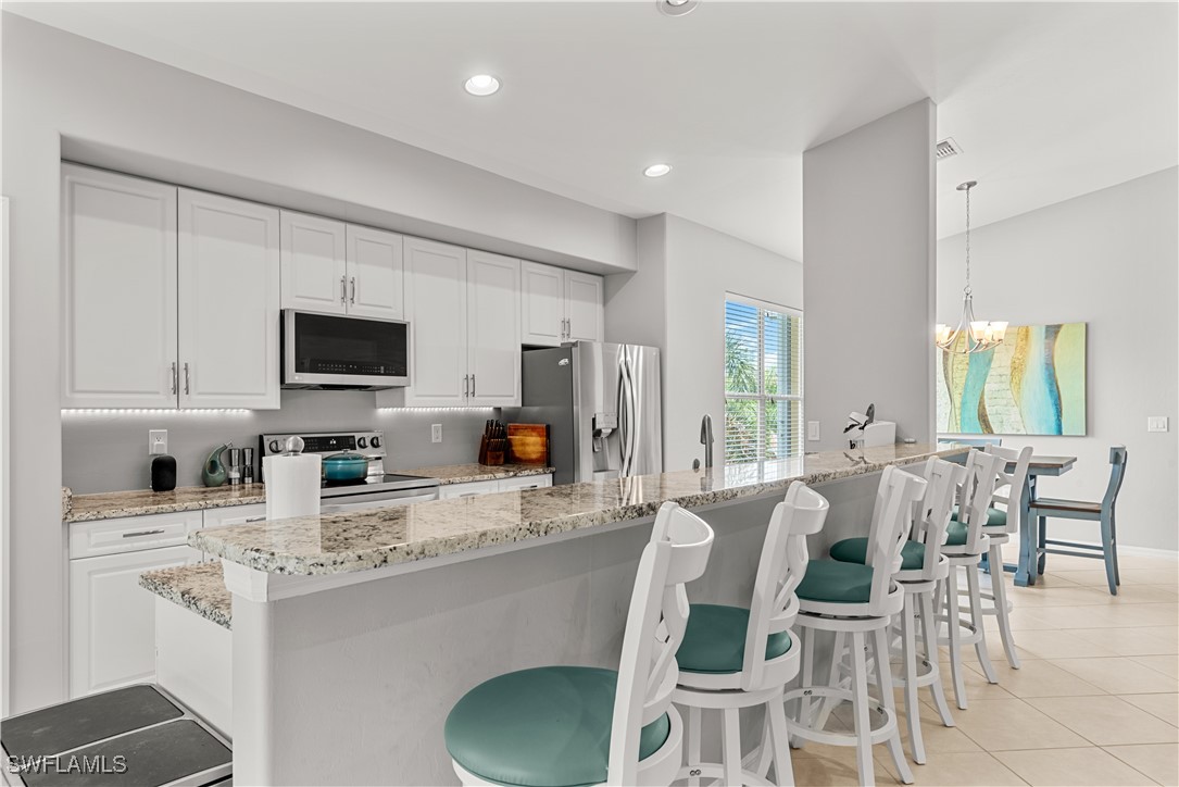 a kitchen with stainless steel appliances kitchen island granite countertop a stove a sink a dining table and chairs