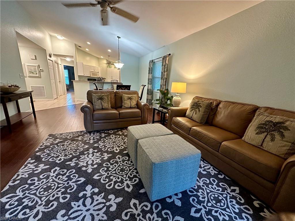 Living room featuring Leather Furniture, ceiling fan, vaulted ceiling, and  wood flooring