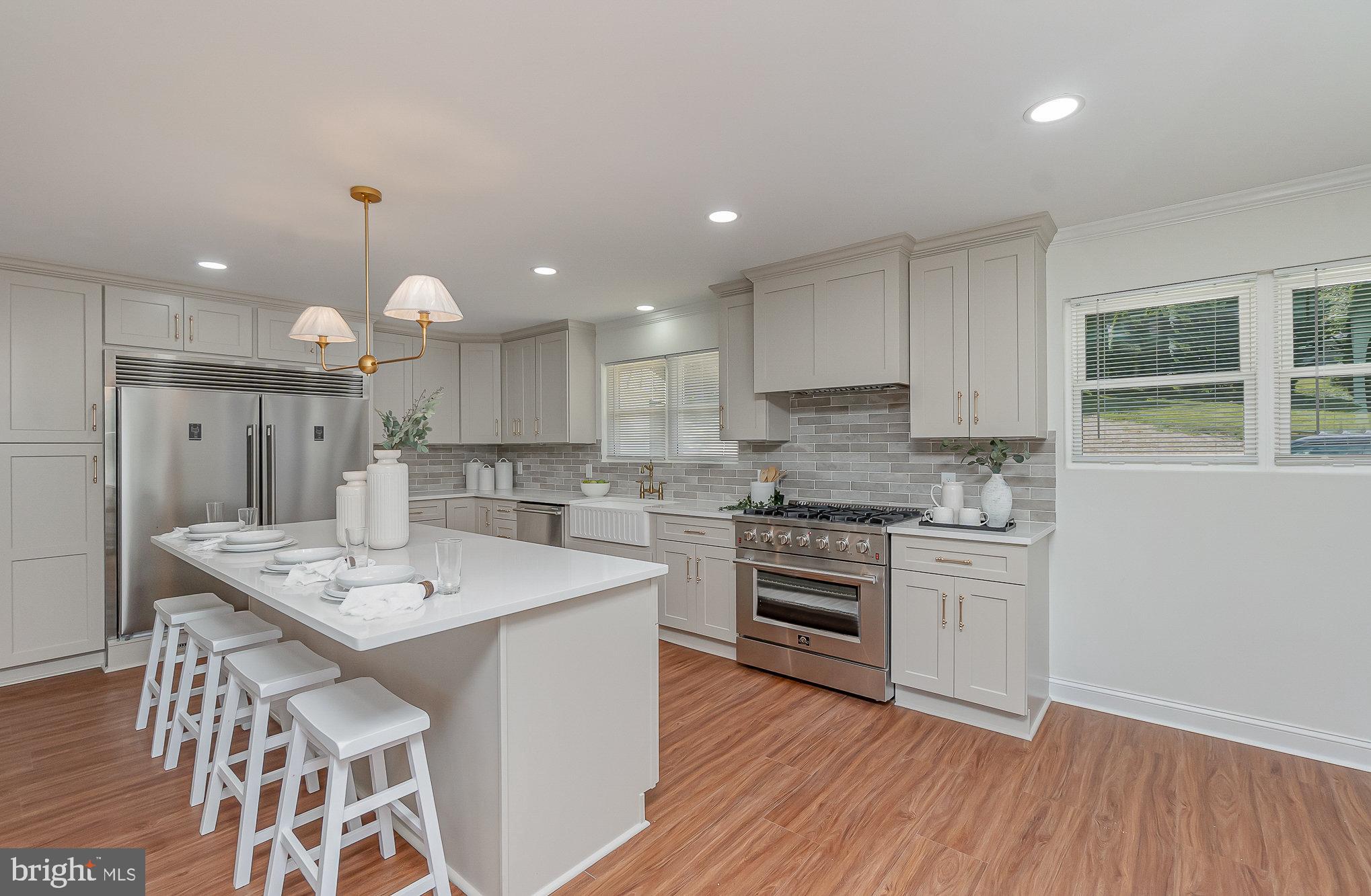 a large kitchen with kitchen island a stove a sink dishwasher and white cabinets with wooden floor