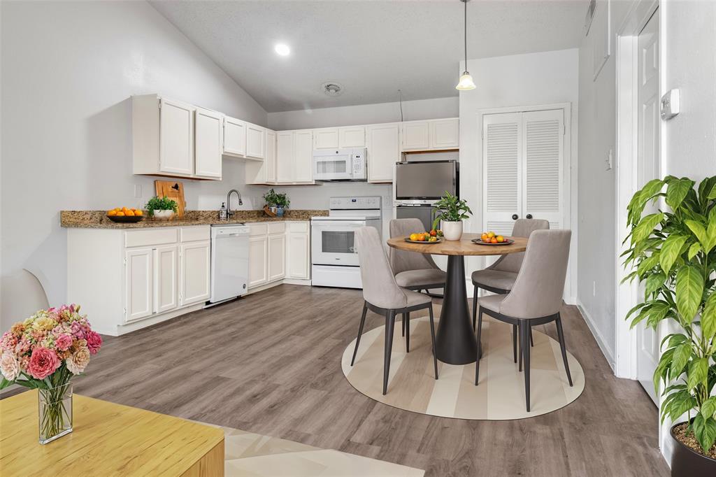 a kitchen with stainless steel appliances kitchen island granite countertop a dining table chairs and white cabinets