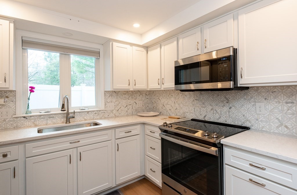 a kitchen with stainless steel appliances granite countertop white cabinets granite counter tops and a window