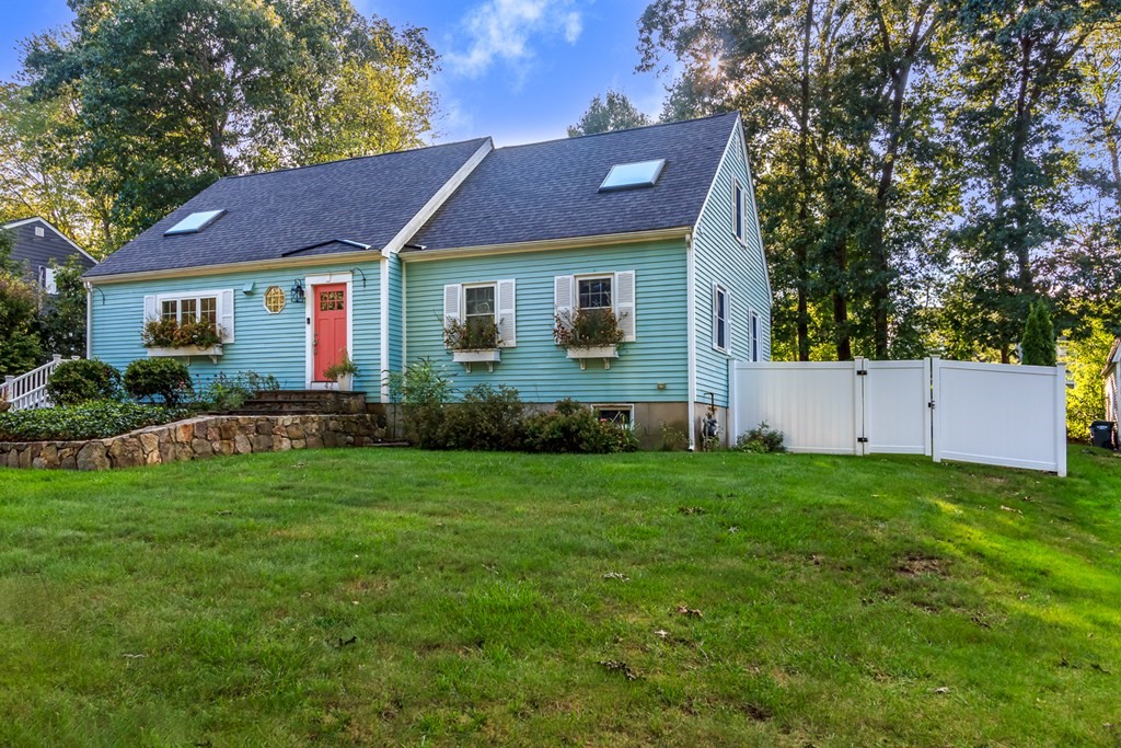 a view of a yard in front of a house with plants and large tree