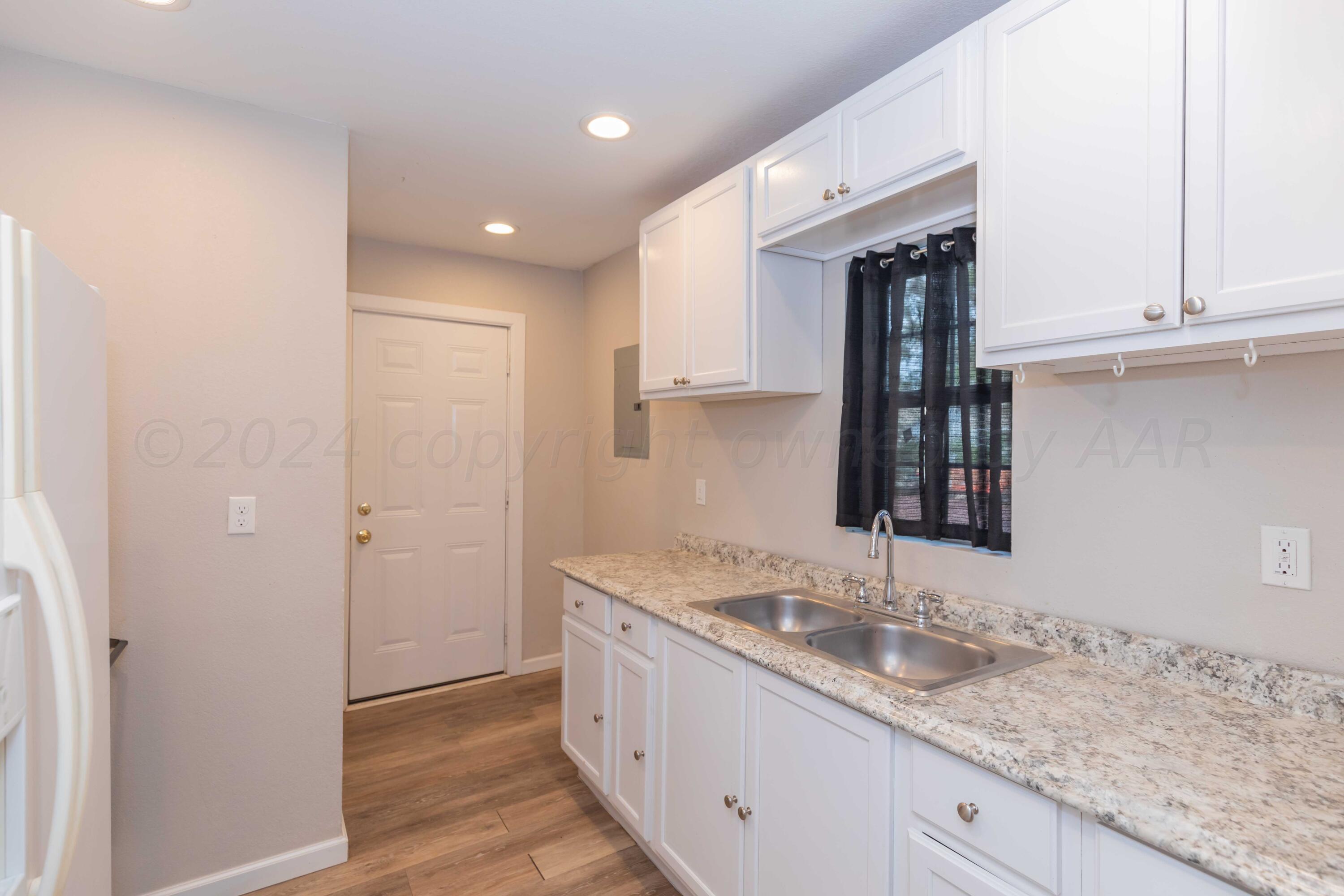 a bathroom with a granite countertop sink mirror and cabinets