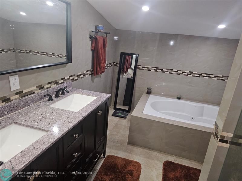 a bathroom with a granite countertop sink a mirror and a bathtub