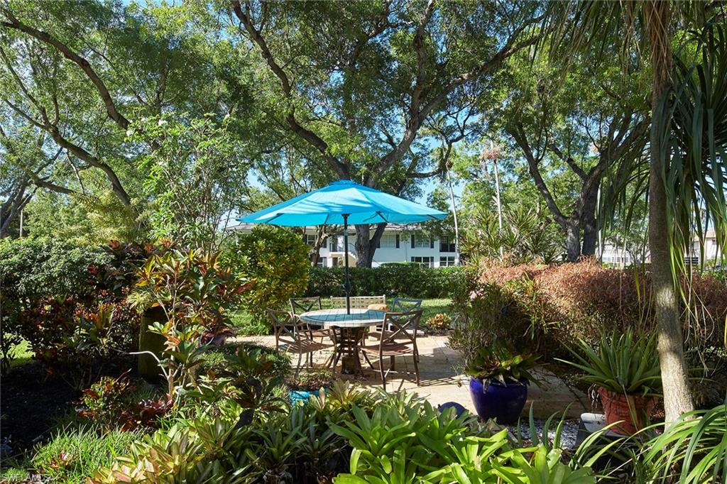 a backyard of a house with table and chairs under an umbrella