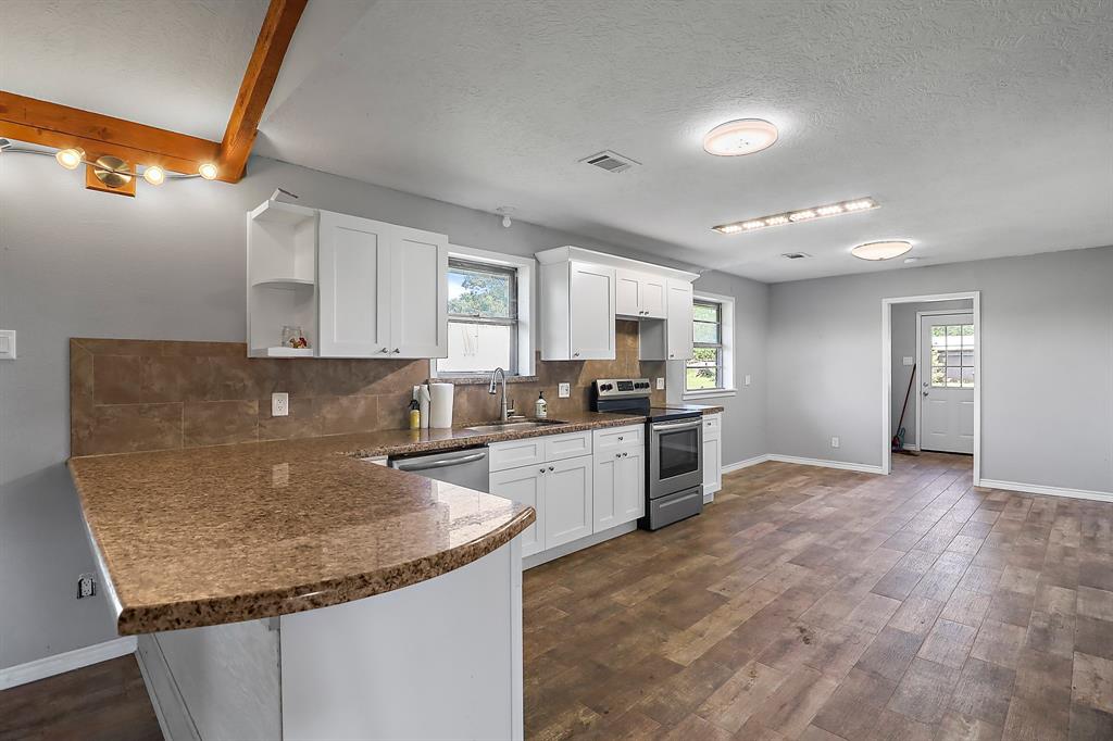 a kitchen with granite countertop a sink a counter top space and cabinets