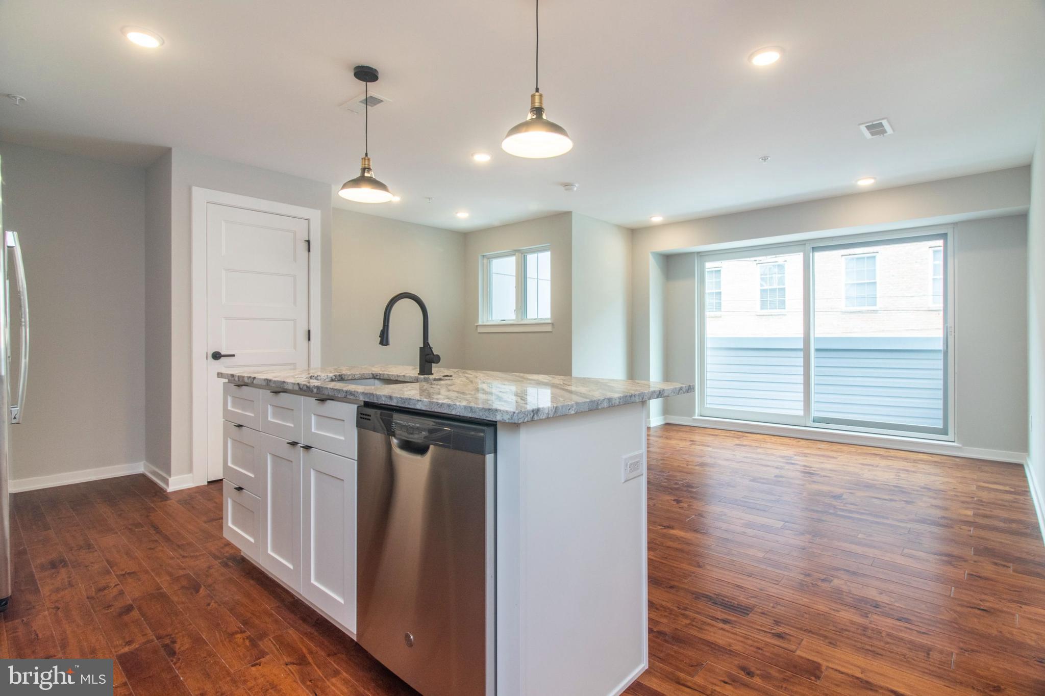 a kitchen with granite countertop a stove a sink and a wooden floor