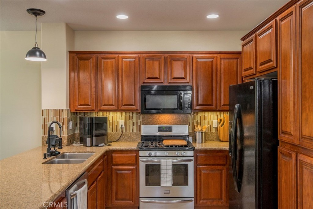 a kitchen with stainless steel appliances granite countertop a refrigerator a stove and a sink with wooden floor