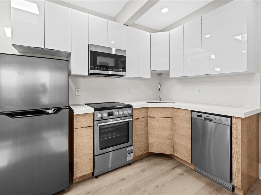 a kitchen with stainless steel appliances white cabinets and a refrigerator