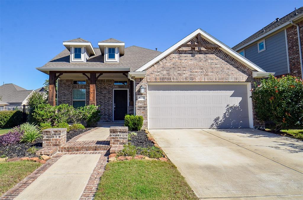 This is a modern single-family home with an attractive brick facade and a two-car garage. The house features a well-maintained front yard with landscaping and a welcoming pathway leading to the front door.