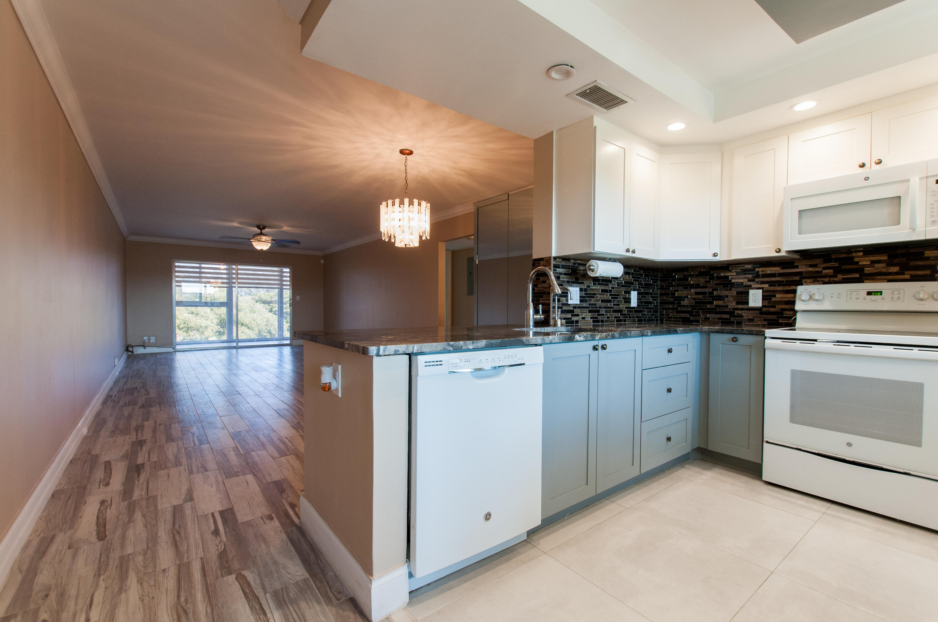 a kitchen with white cabinets a sink dishwasher and a stove with wooden floor