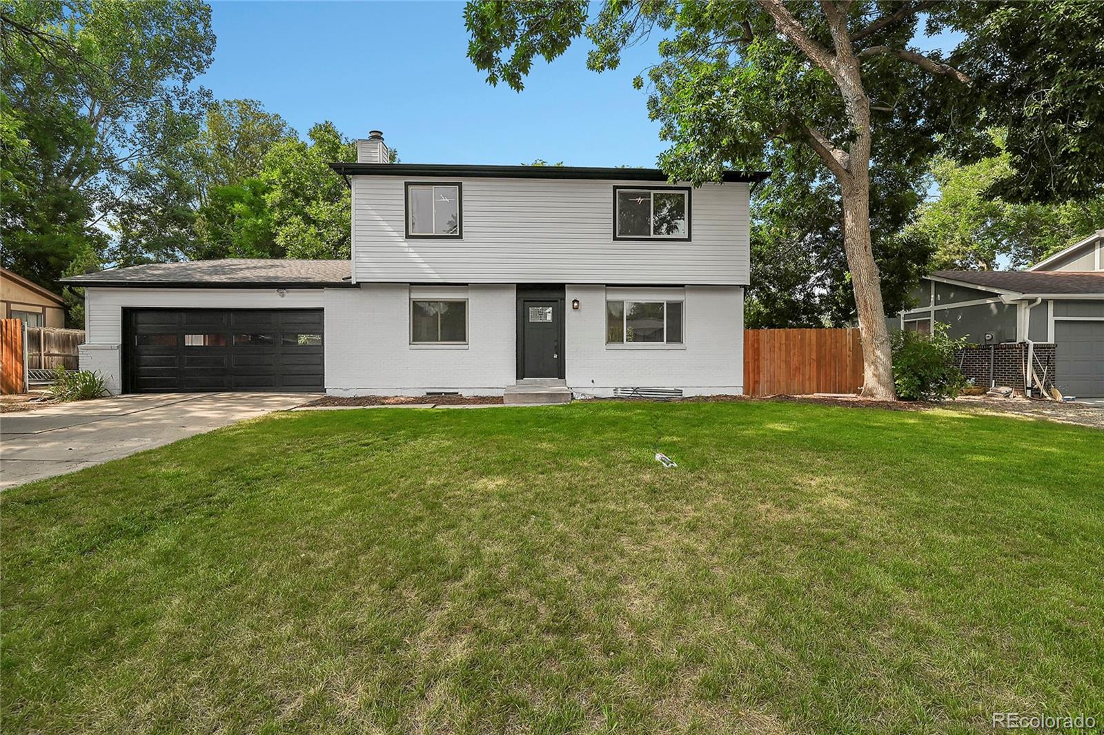 a front view of house with yard and trees in the background