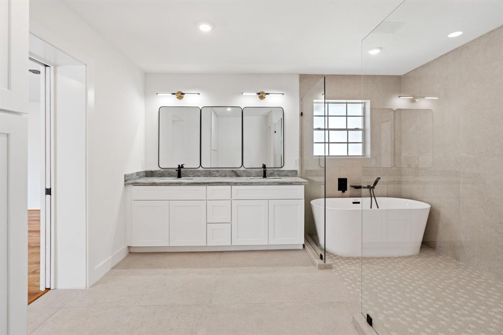 a bathroom with a double vanity sink a mirror and a bathtub