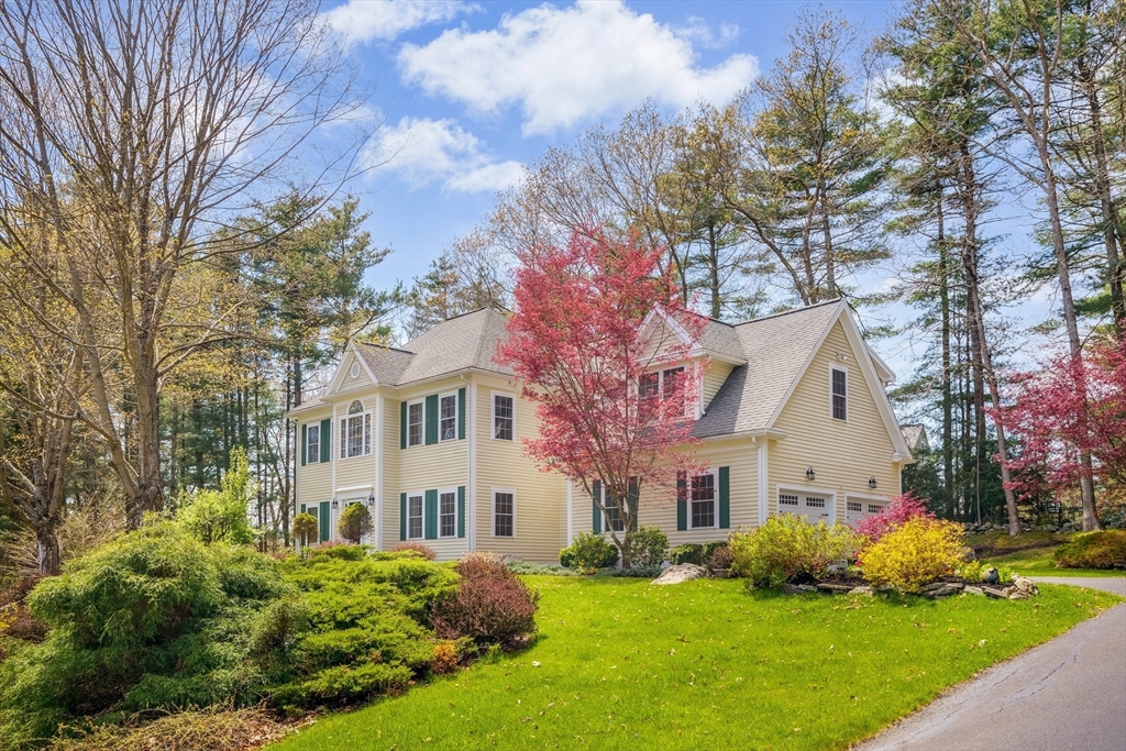 a front view of a house with a garden and trees