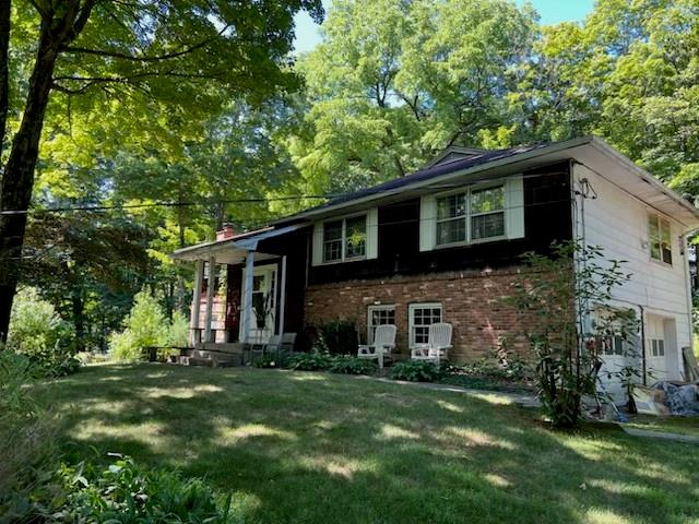 a brick house with a big yard plants and big trees