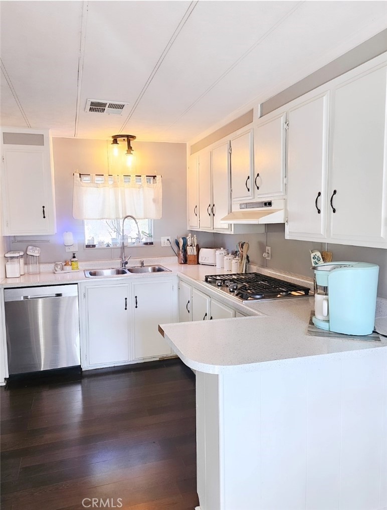 a kitchen with stainless steel appliances a sink a stove a counter space and cabinets