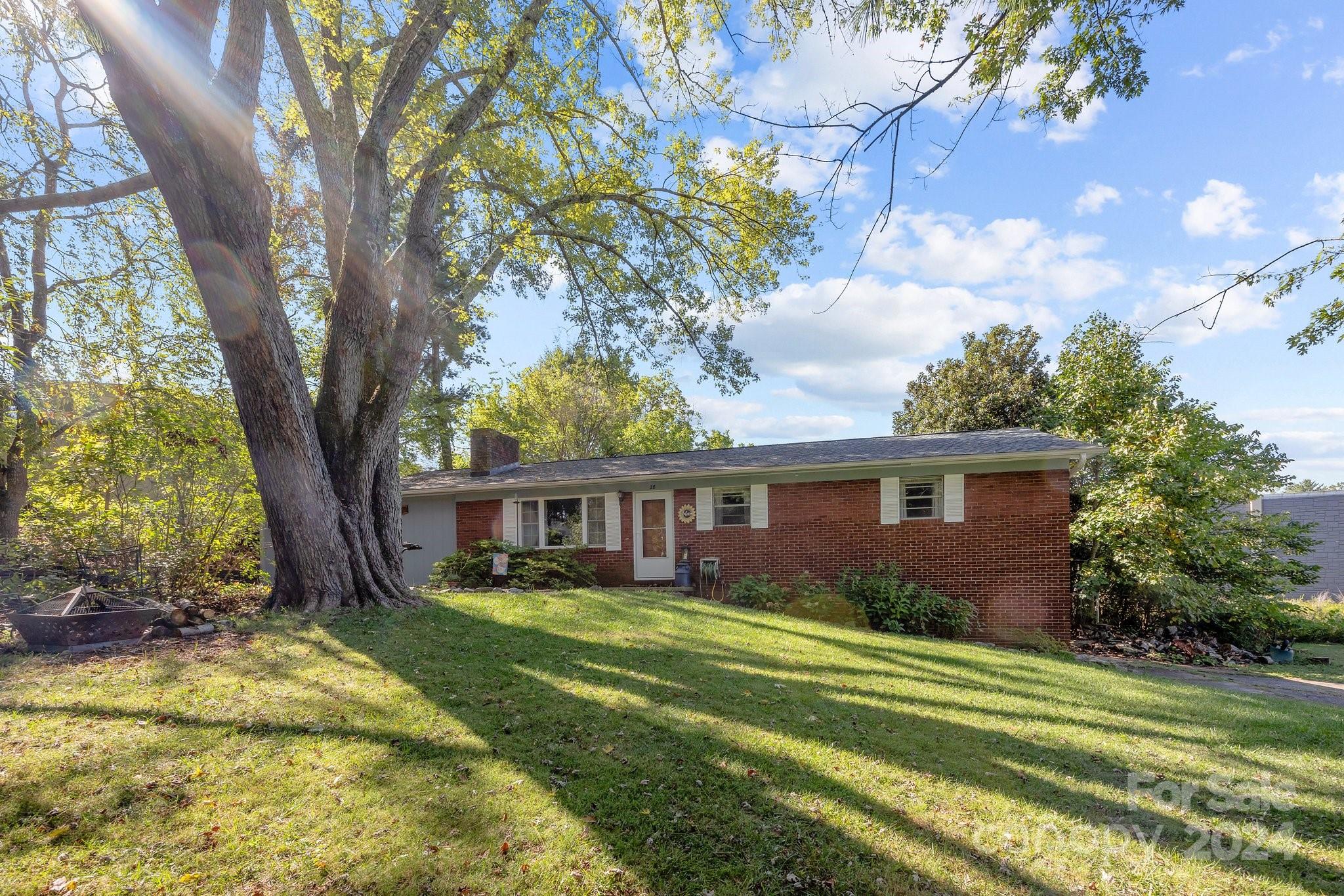 a view of house with a big yard and large trees