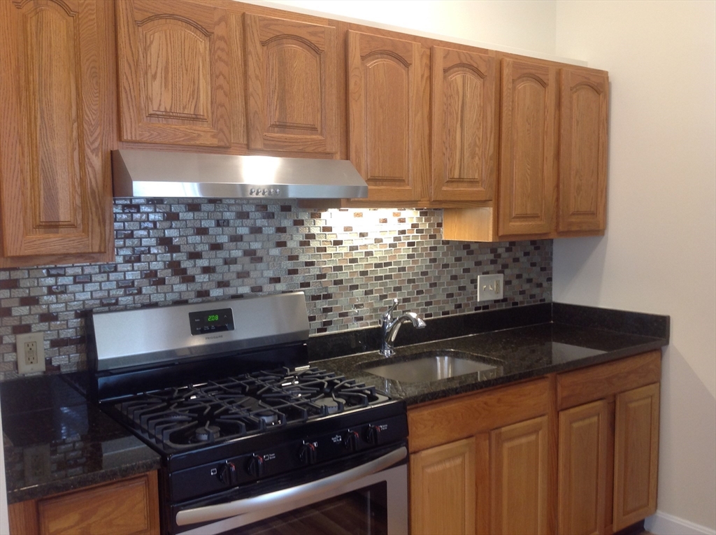 a kitchen with granite countertop a stove sink and cabinets