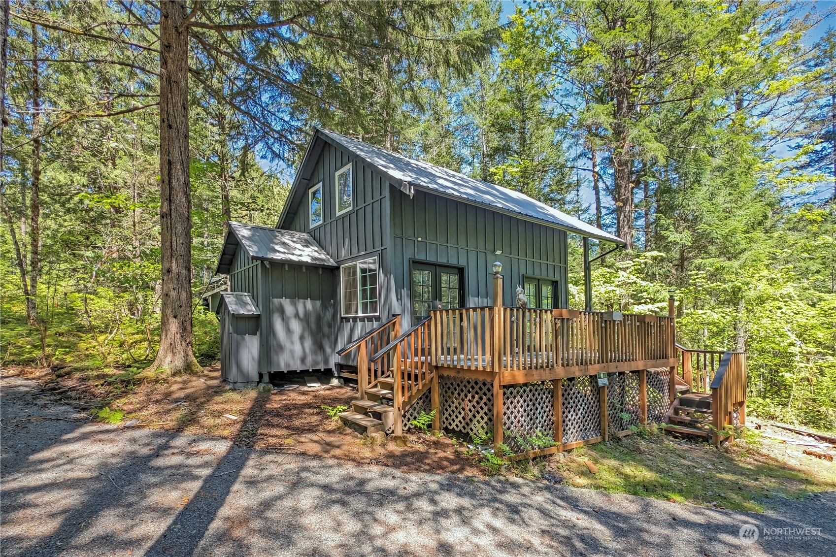 a view of wooden house with large trees and wooden fence