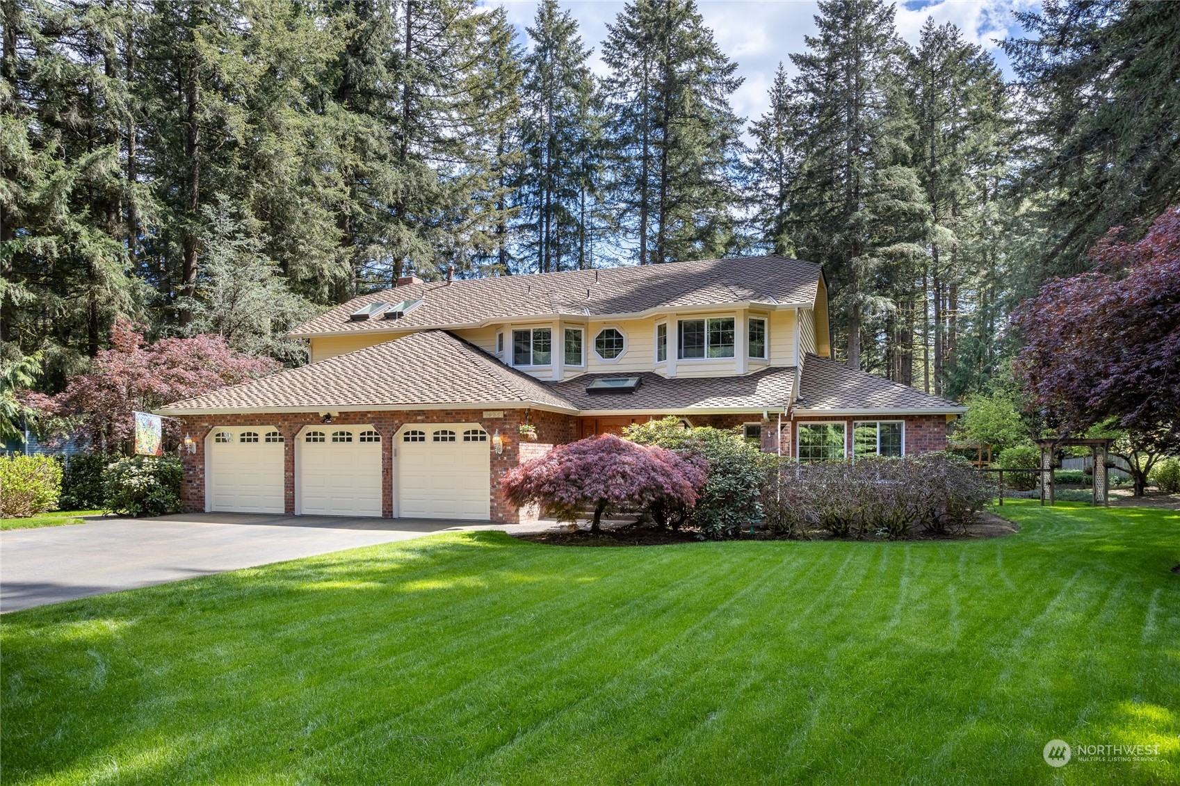 a front view of a house with a garden and trees