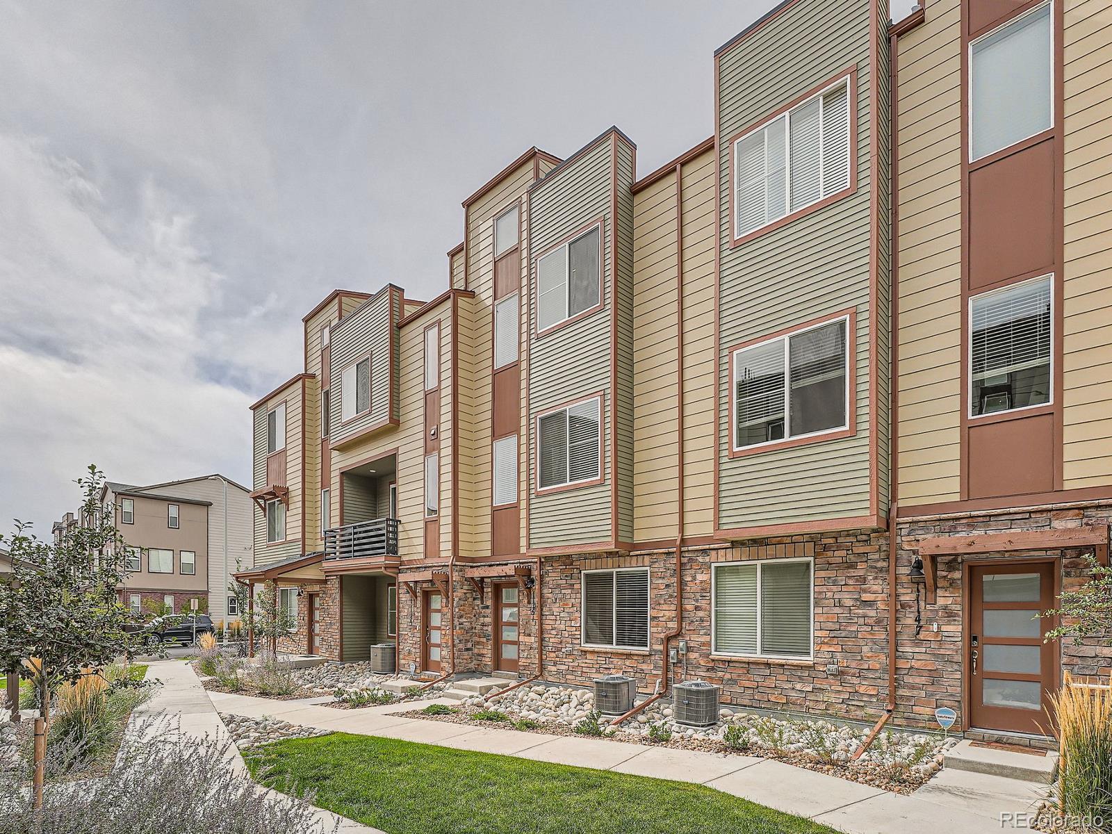 a front view of a residential apartment building with yard and parking space