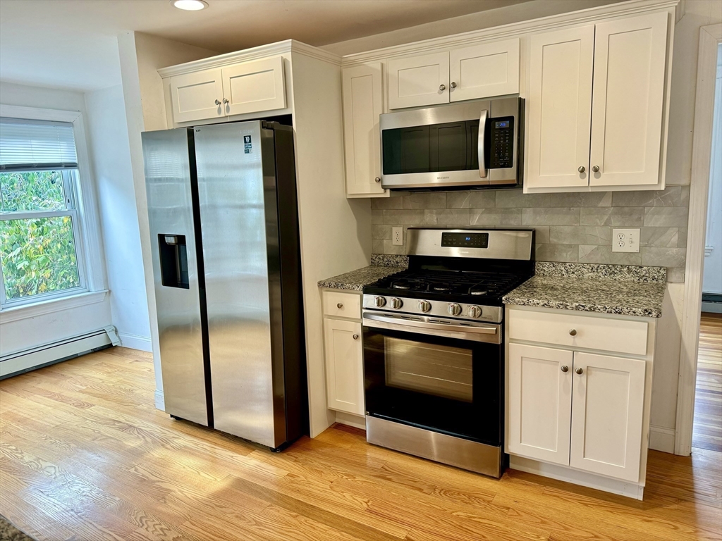 a kitchen with stainless steel appliances granite countertop a stove a microwave and a white refrigerator