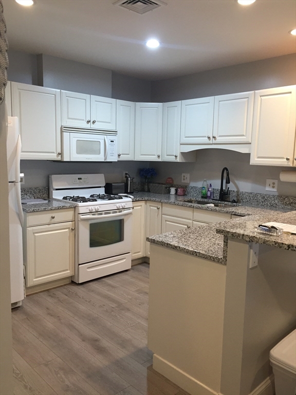 a kitchen with granite countertop white cabinets and white appliances