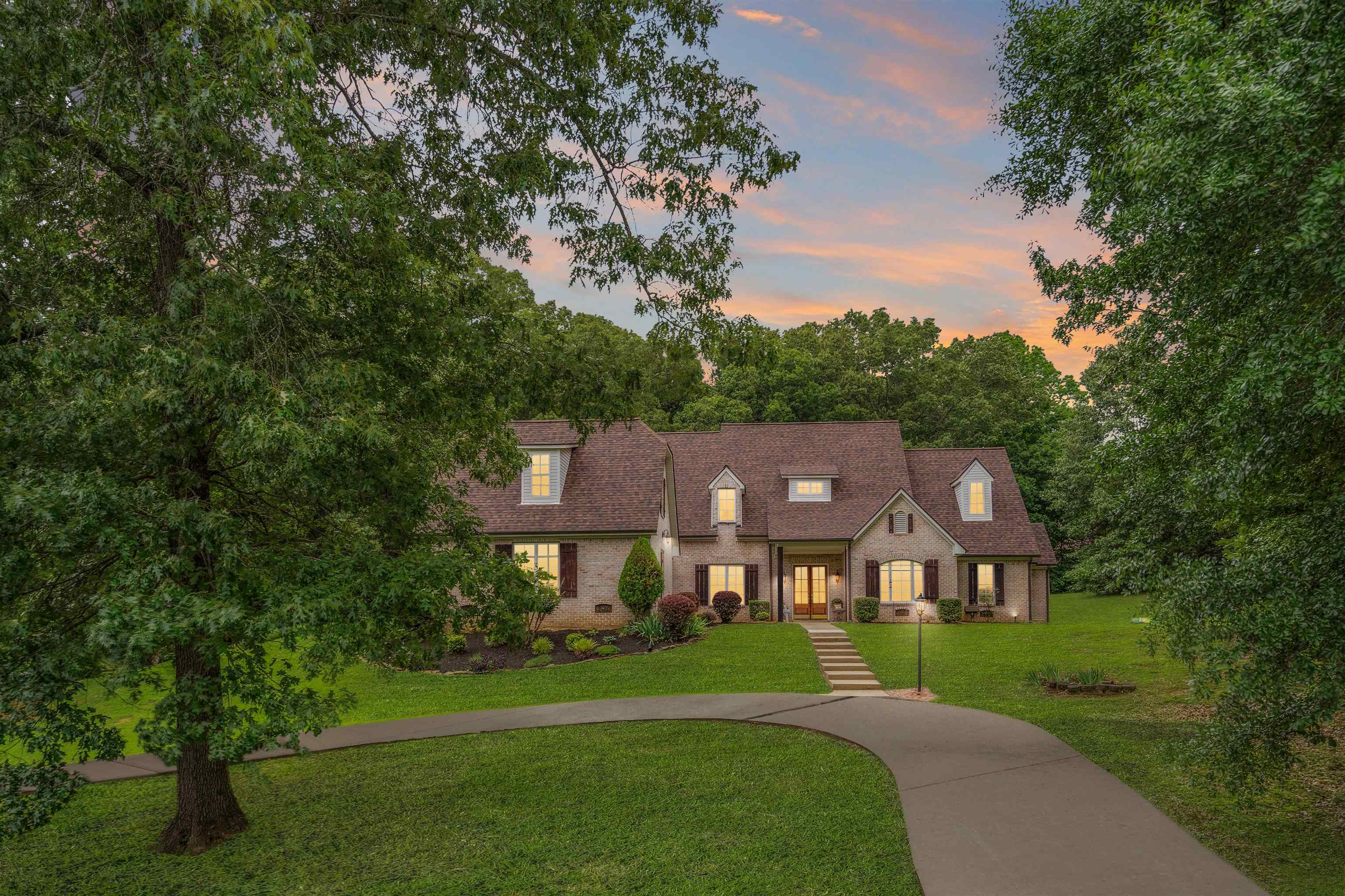 a view of a big house with a big yard and large trees