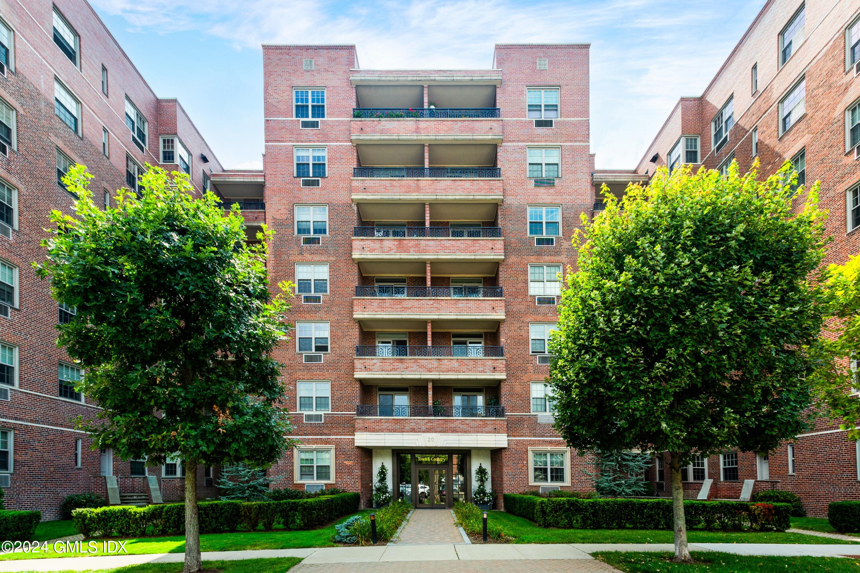 a front view of multi story residential apartment building with yard and green space