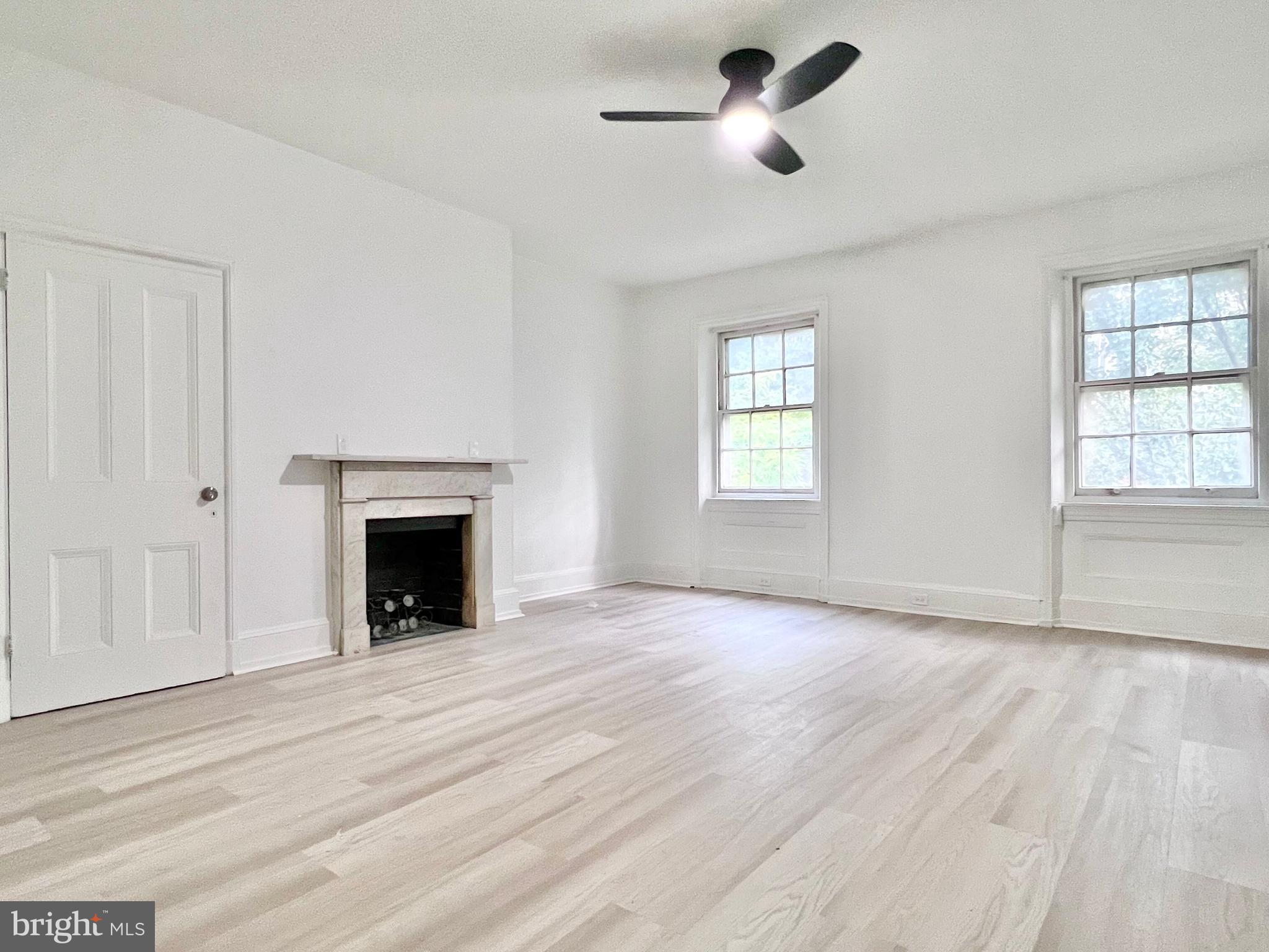 an empty room with windows and fireplace