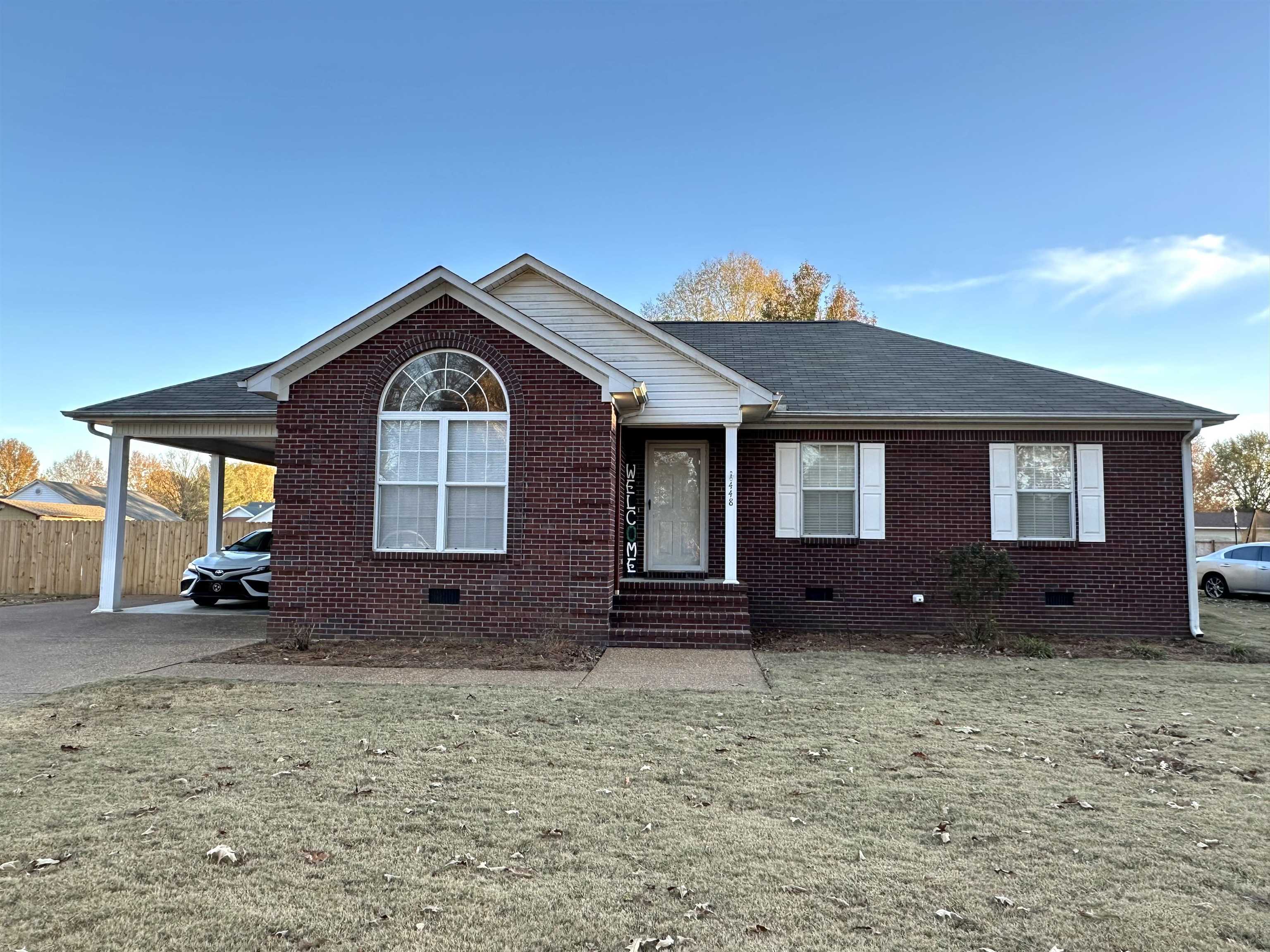 View of front of home with a front yard and a carport