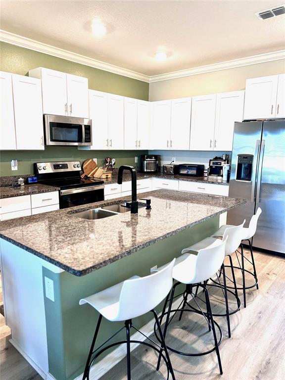 a kitchen with stainless steel appliances granite countertop a table chairs sink and cabinets