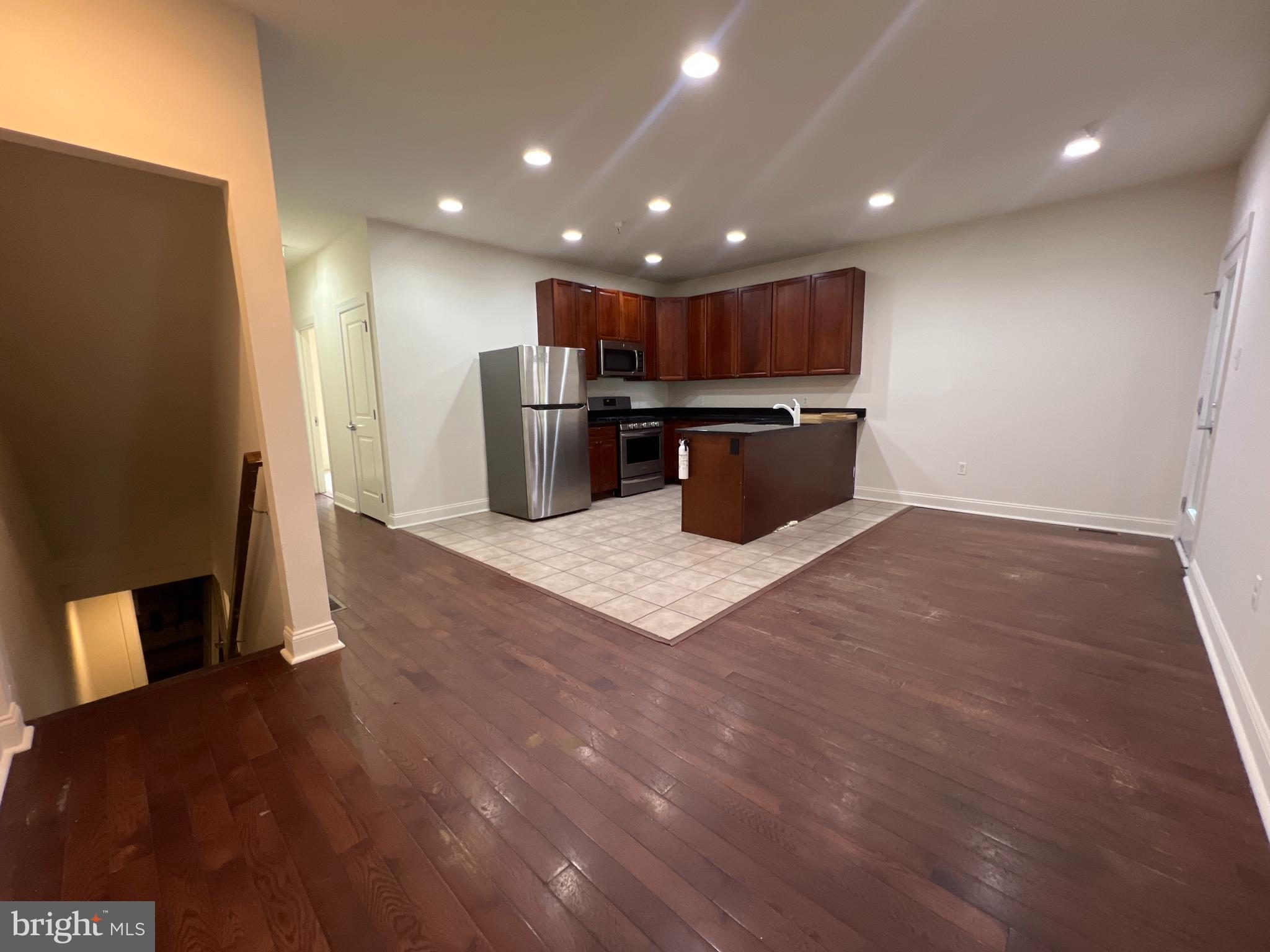 a kitchen with stainless steel appliances a refrigerator and wooden floor