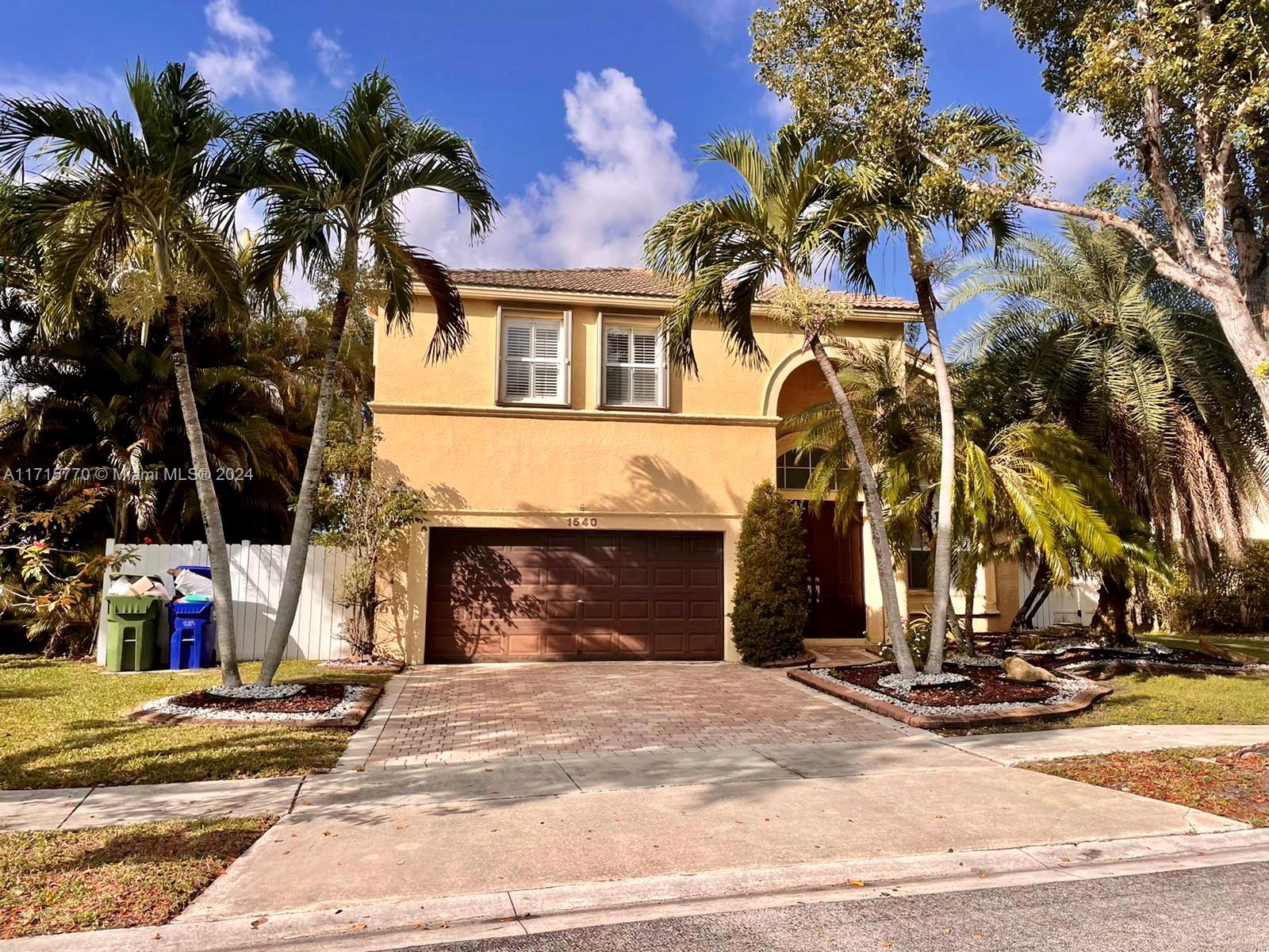 a front view of a house with garage and plants