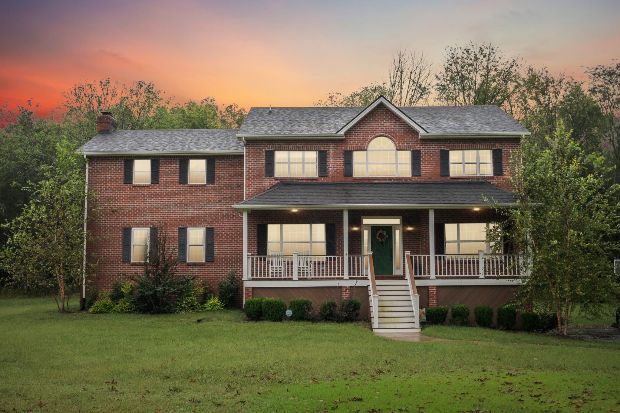 a front view of a house with a yard and green space