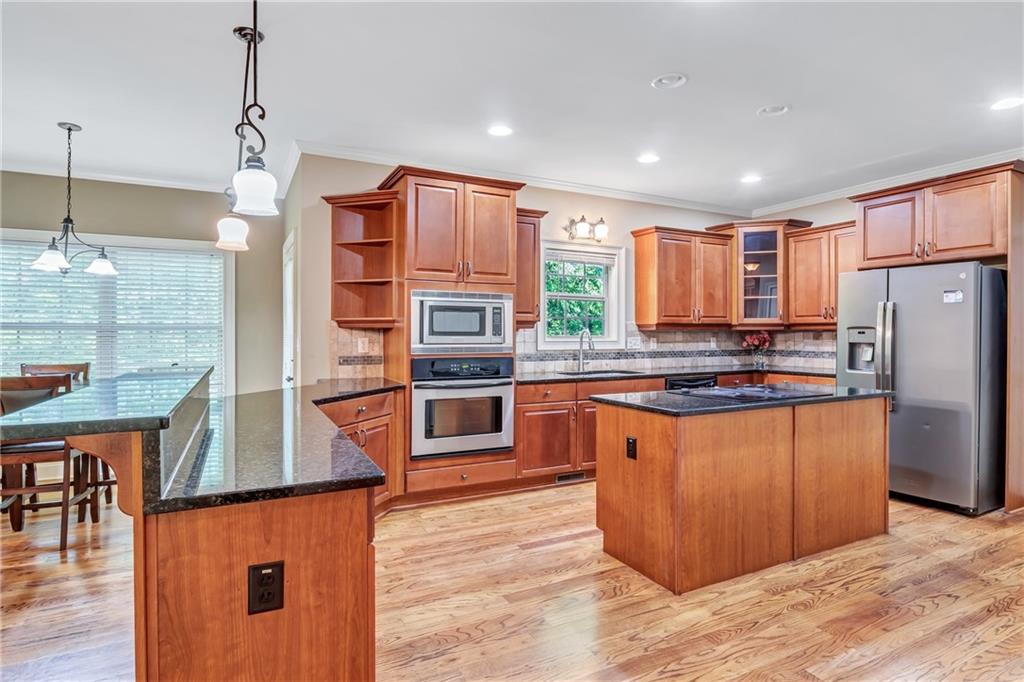 a kitchen with stainless steel appliances granite countertop a refrigerator a stove and a wooden floors