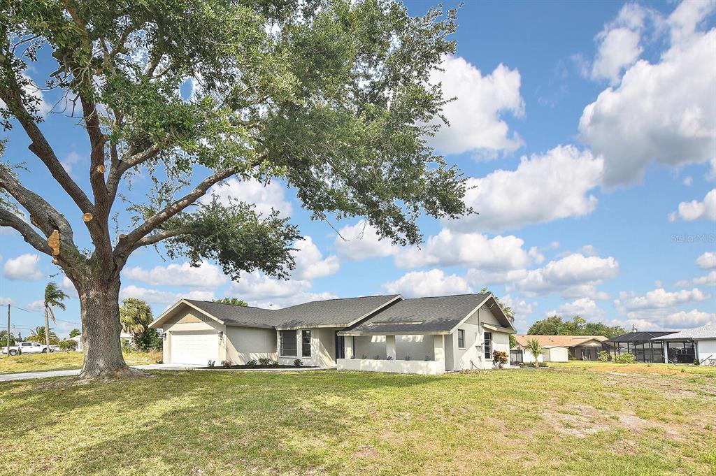 a white house with a big yard and large trees