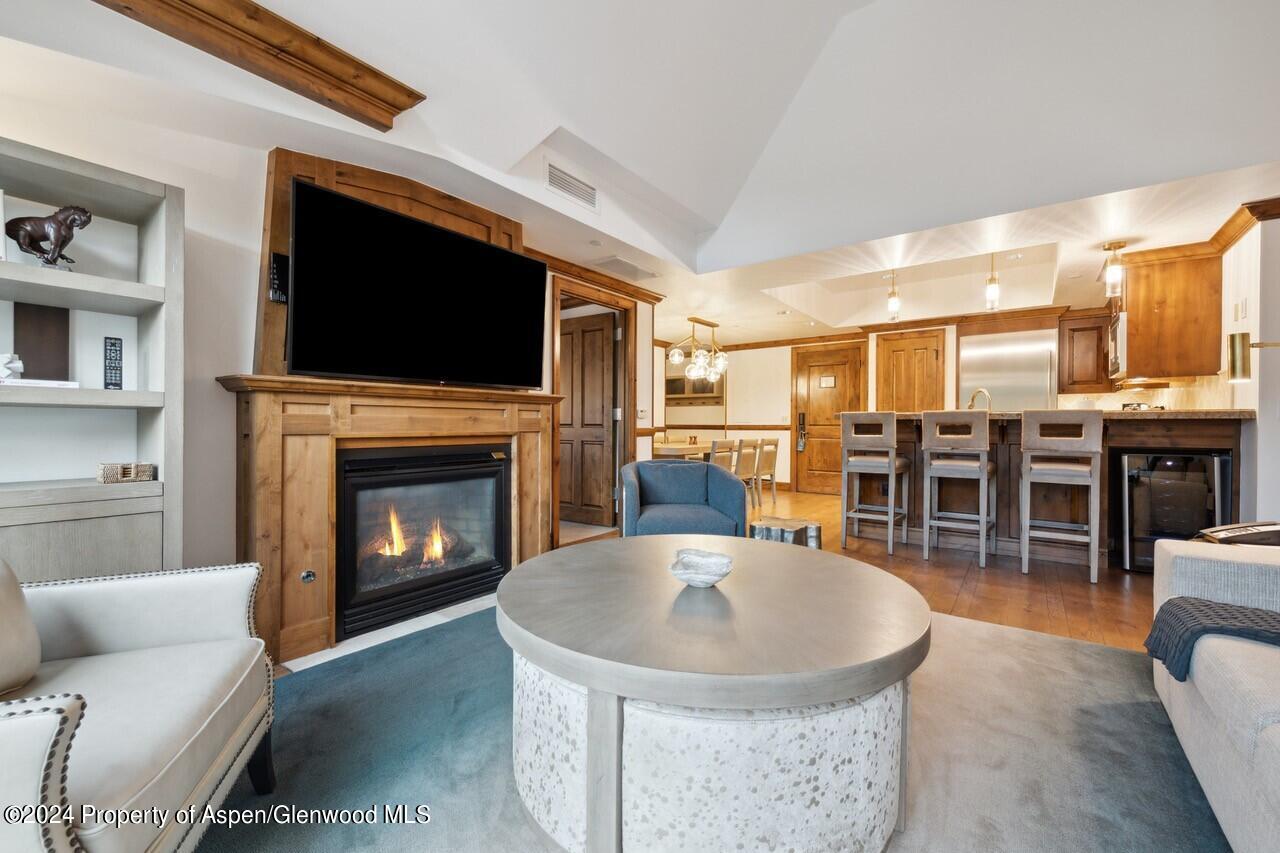 a living room with stainless steel appliances furniture a fireplace and a flat screen tv