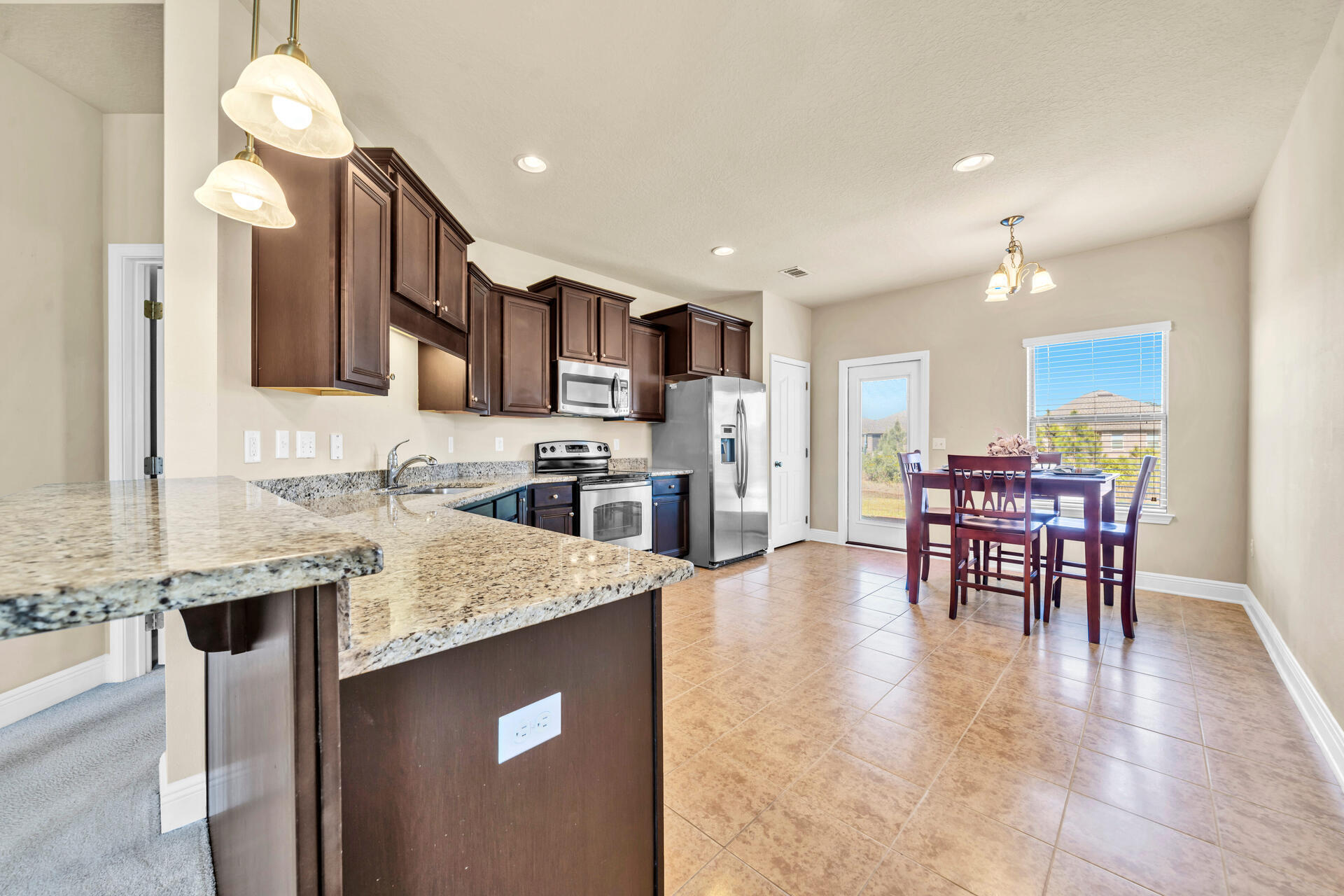 a kitchen with stainless steel appliances granite countertop a table chairs sink and cabinets