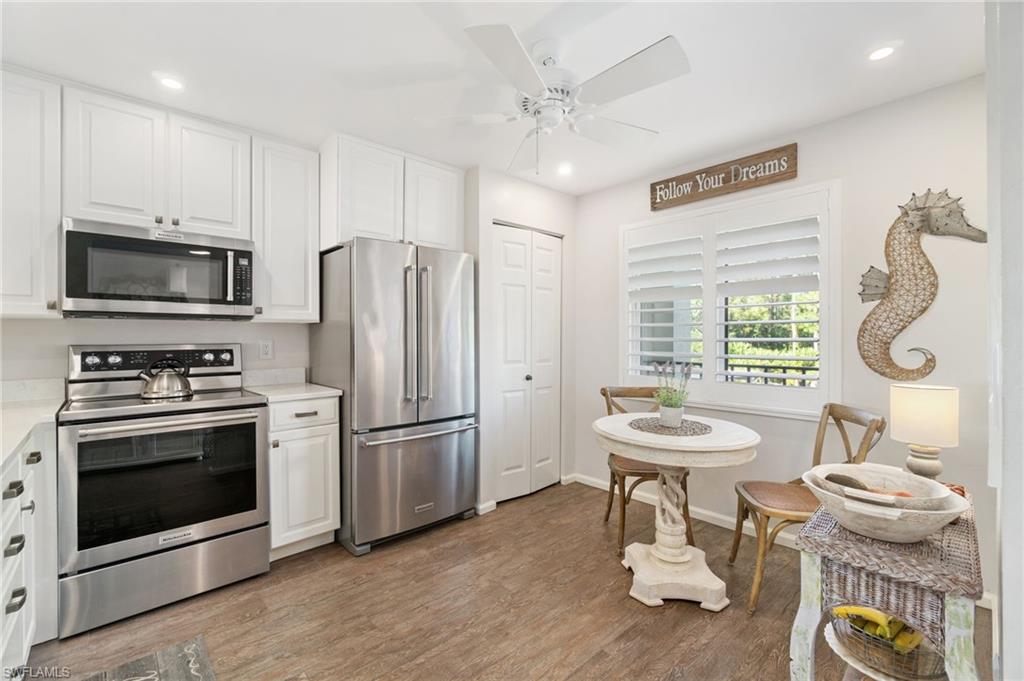 Kitchen with white cabinets, ceiling fan, wood-type flooring, and appliances with stainless steel finishes