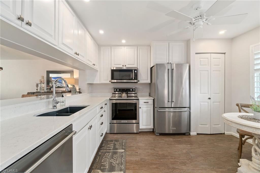 Kitchen featuring sink, appliances with stainless steel finishes, ceiling fan, dark hardwood / wood-style floors, and white cabinets