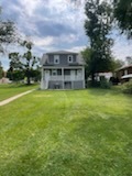 a view of a house with a big yard and a large tree