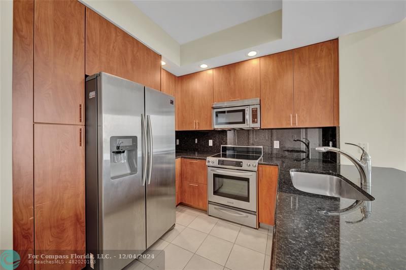 a kitchen with stainless steel appliances granite countertop a refrigerator a stove a sink and a microwave