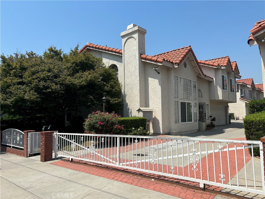 a view of a brick house with iron fence