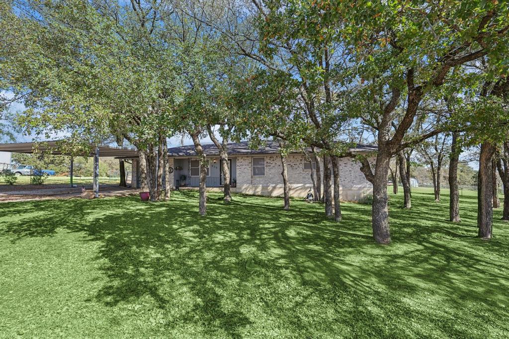 a big yard with table and chairs and large trees