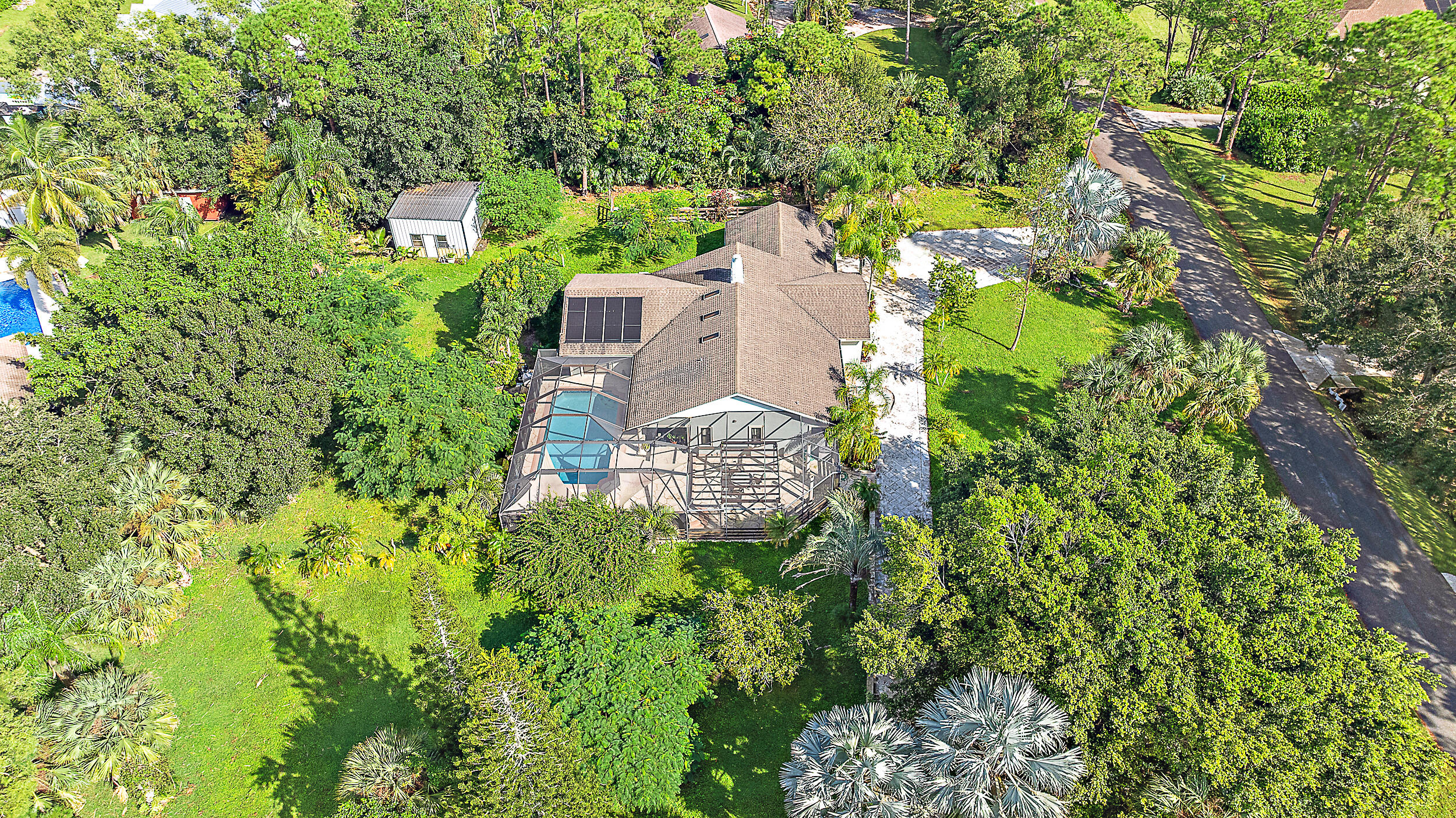 an aerial view of residential house with outdoor space and trees all around