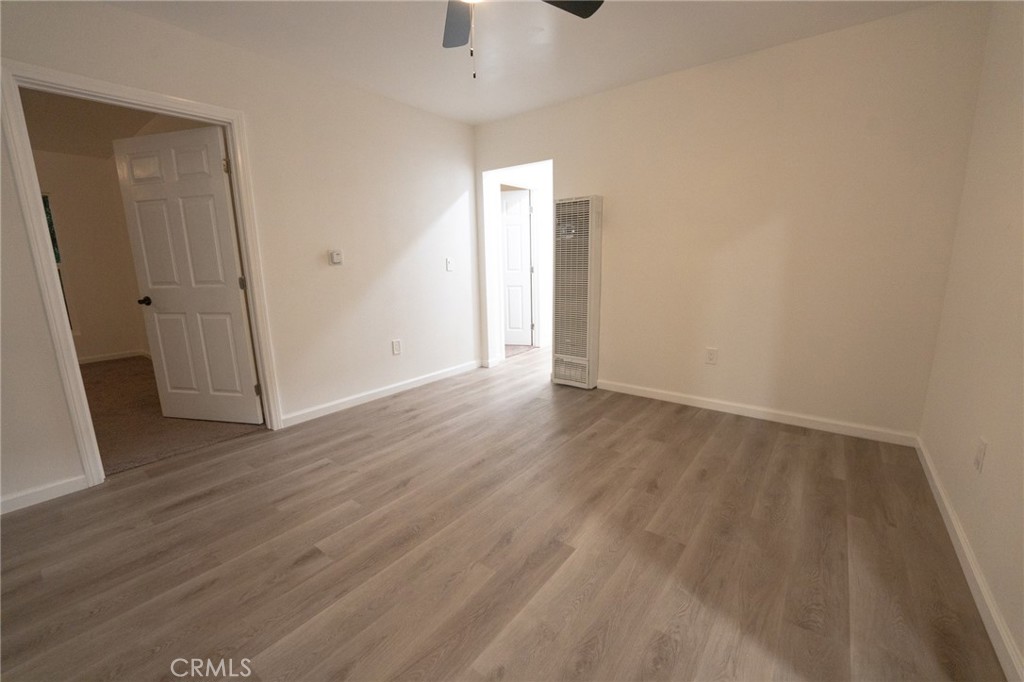 an empty room with wooden floor and a ceiling fan