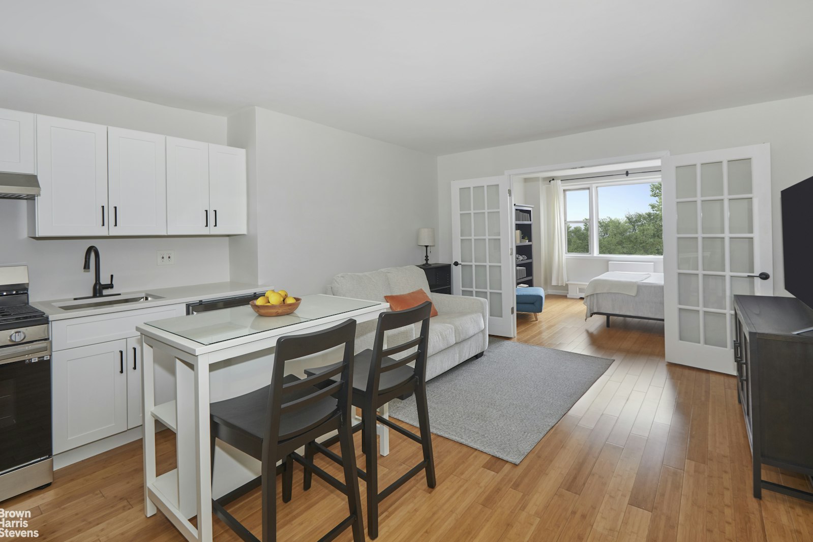 a living room with a kitchen view and a wooden floor