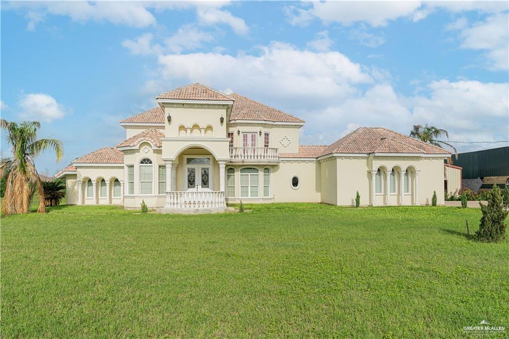 Rear view of property with a yard, french doors, and a balcony